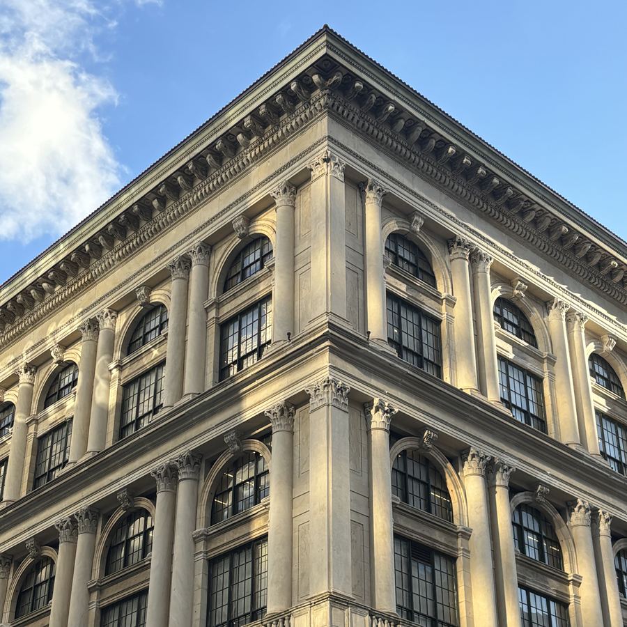 A carved stone and cast-iron corner building in late-afternoon sun against a blue sky